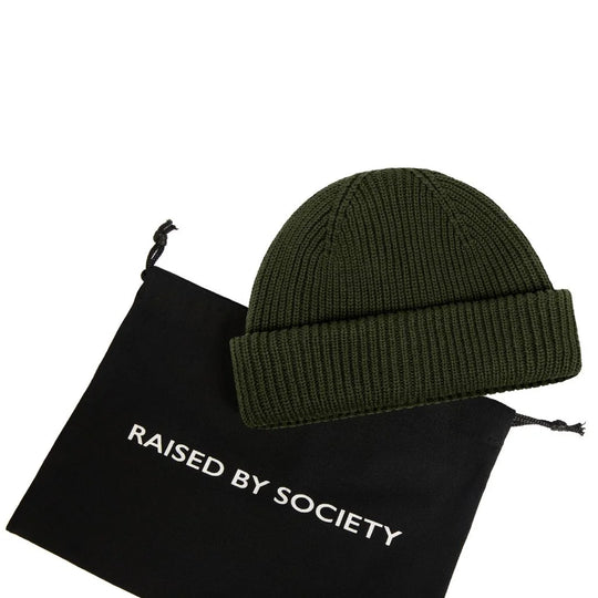 fisherman beanie not too warm. Green beanie on a black drawstring bag with 'Raised by Society' text on a white background. 